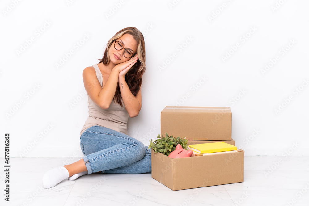 Young Russian girl sitting on the floor isolated on white background making sleep gesture in dorable expression Young Russian girl sitting on the floor isolated on white background making sleep gesture in dorable expression