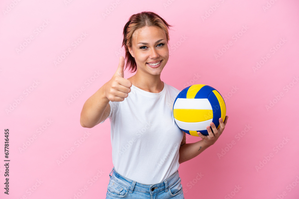 Young Russian woman playing volleyball isolated on pink background with thumbs up because something good has happened