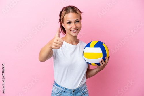 Young Russian woman playing volleyball isolated on pink background with thumbs up because something good has happened © luismolinero