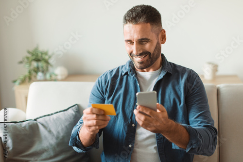 buyer guy uses phone to shop holds credit card indoors