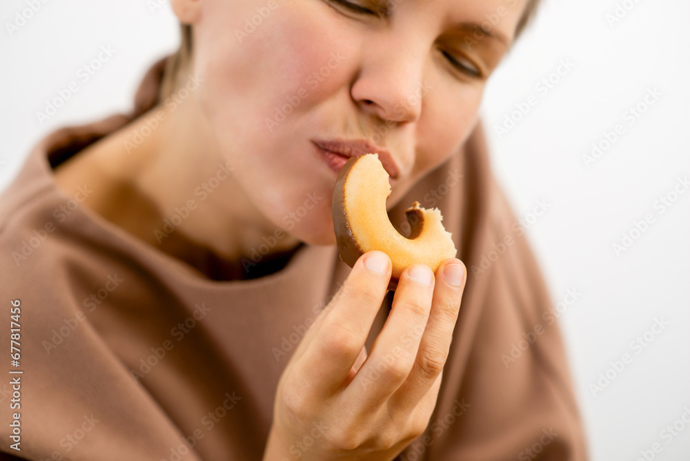 Decadent delight: An attractive woman in her prime relishing the sinful pleasure of a chocolate-covered donut