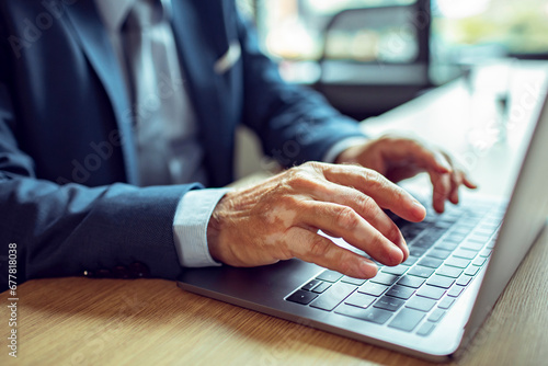 Close-up of a Businessman's Hands Typing on a Laptop Keyboard photo
