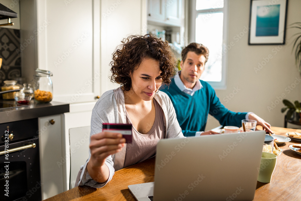 Young couple online shopping in the morning while having breakfast on their laptop Young couple online shopping in the morning while having breakfast on their laptop
