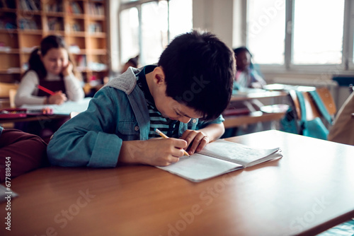 Little boy taking notes in classroom photo