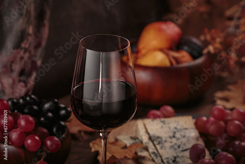 Glass of red wine served with blue cheese on dark wooden background. Autumn picnic with wine and cheese platter  fruits and dry leaves in rustic style