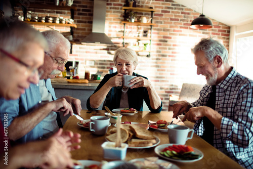 Senior people sitting at dining table together having breakfast photo