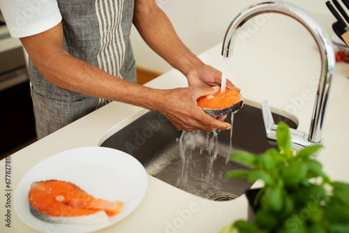 Foto African man rinsing ingredients for nutritious salmon dish at kitchen