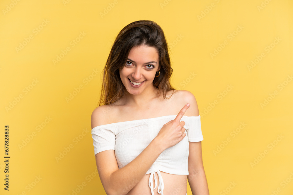 Young caucasian woman isolated on yellow background pointing to the side to present a product Young caucasian woman isolated on yellow background pointing to the side to present a product