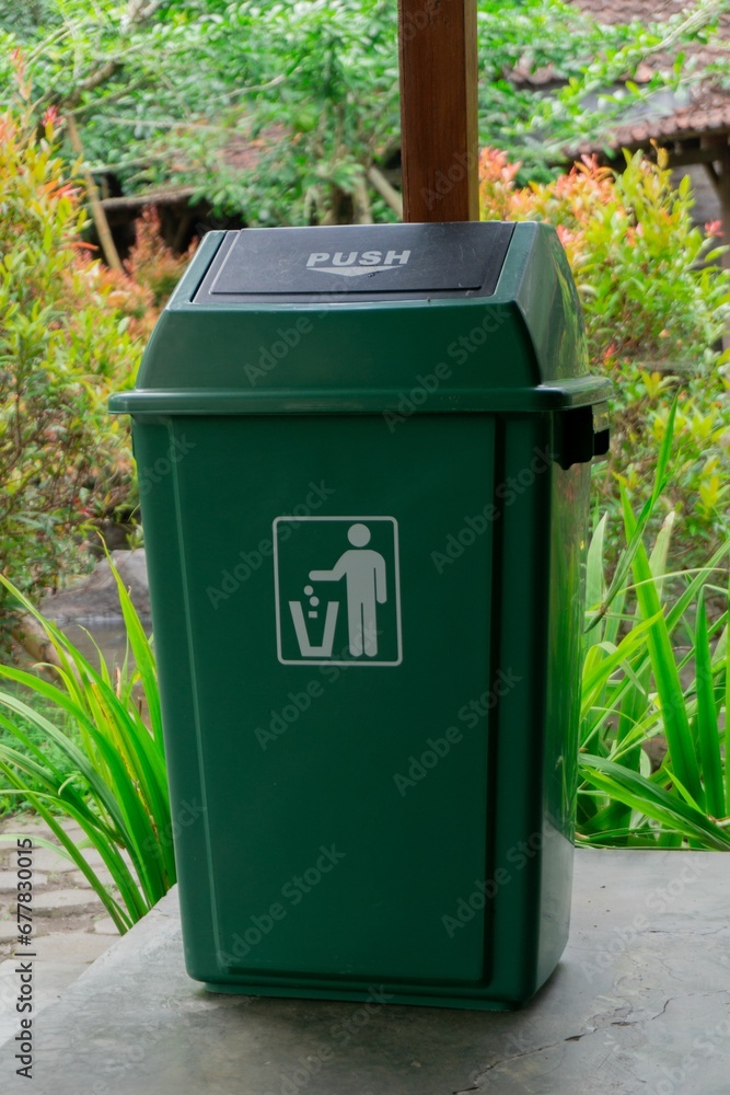 Vertical closeup of a green garbage can in the garden. Vertical closeup of a green garbage can in the garden.