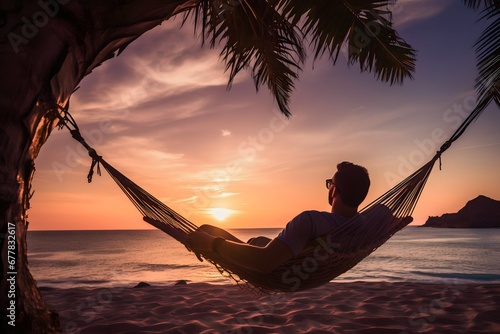 man relaxing in a hammock on the beach at sunset photo