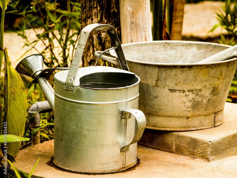 Close-up shot of a garden watering can and a steel bowl Close-up shot of a garden watering can and a steel bowl