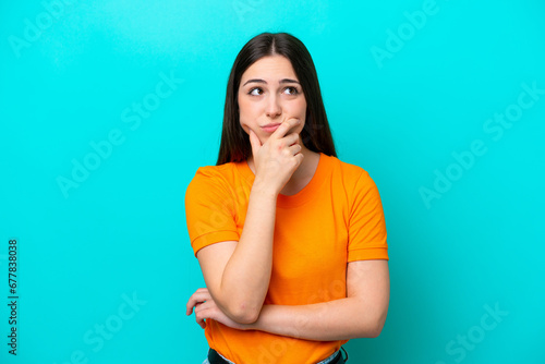 Young caucasian woman isolated on blue background having doubts photo