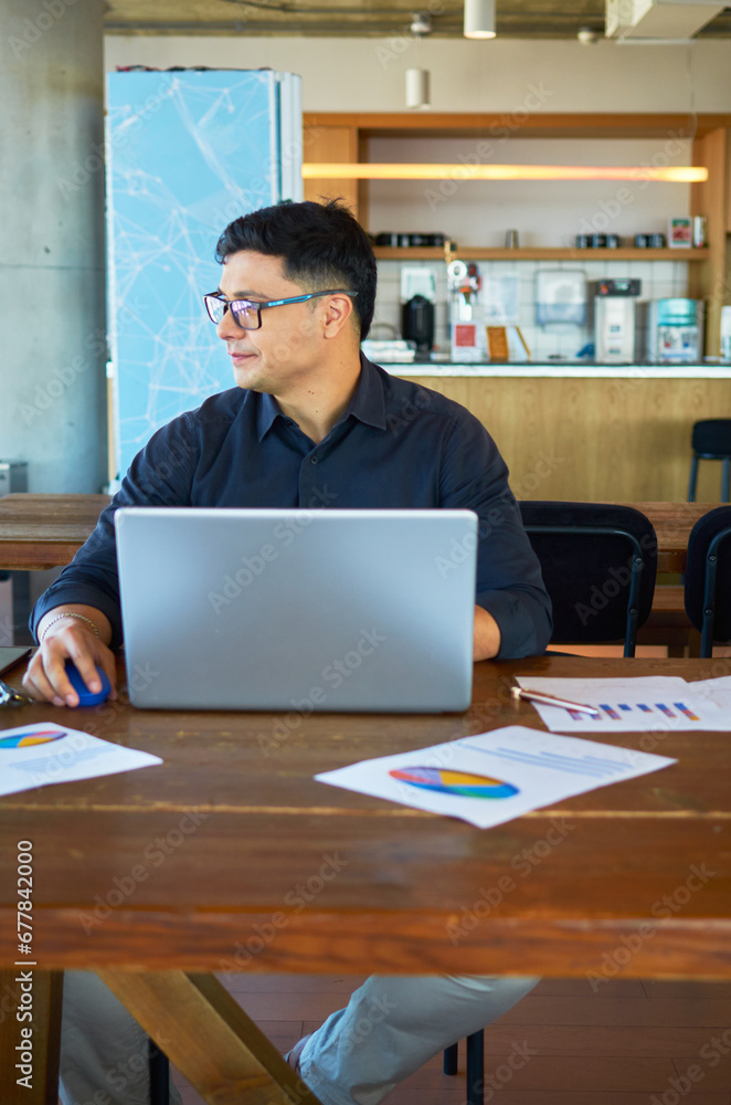Young business professional smiling and working with his laptop in a coworking space. Young business professional smiling and working with his laptop in a coworking space.