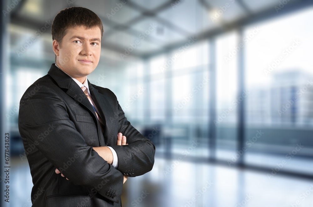 Smiling confident business man standing in office Smiling confident business man standing in office