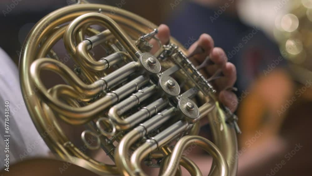 A musician playing a French horn during and classical orchestra rehearsal