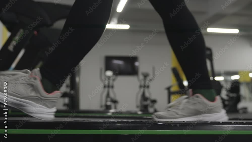 A Woman is Slowly Walking on a Treadmill in the Gym. The Athletic Life in Motion. A Woman is Slowly Walking on a Treadmill in the Gym. The Athletic Life in Motion.