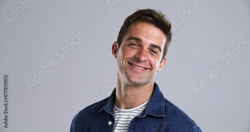 Face, smile and a handsome young man in studio isolated on gray background to relax while feeling positive. Portrait, confident and casual with a happy person from Brazil looking carefree or natural photo