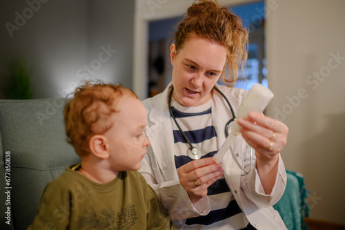 Pediatrician at home visit showing medicine to a sick boy.