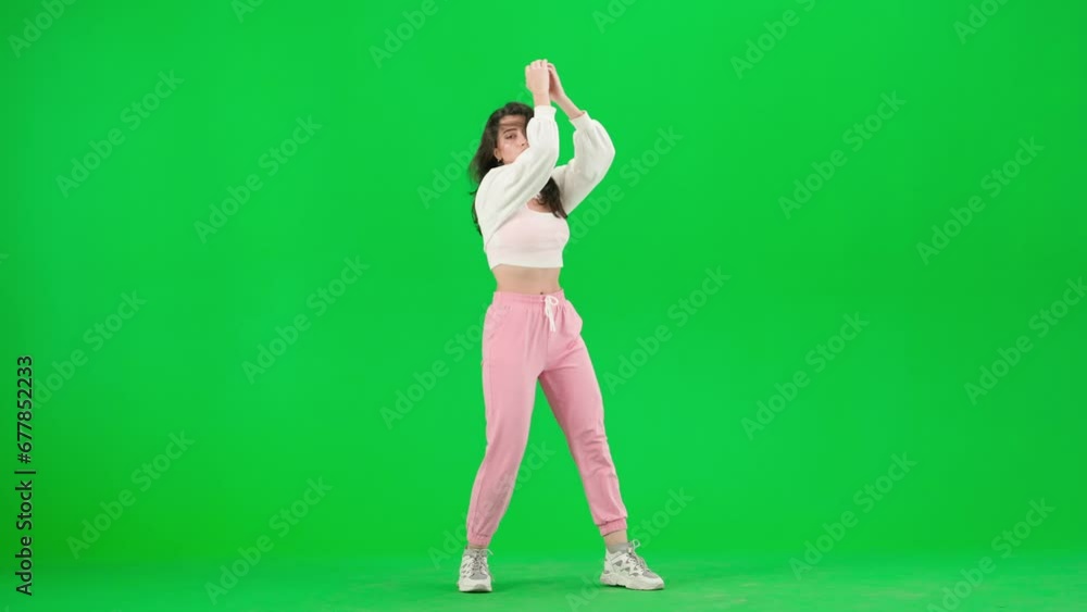 Attractive woman in pink pants dancing sensual jazz funk choreography on chroma key green screen background in a studio. Attractive woman in pink pants dancing sensual jazz funk choreography on chroma key green screen background in a studio.