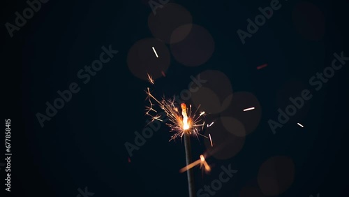 Burning sparkler on black background with lens flare lights. New year party background. New year sparkles.