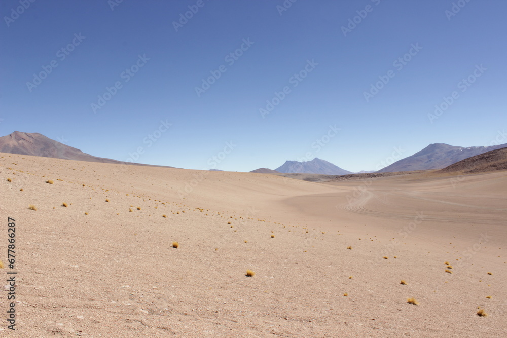 Bolivian Desert Under Clear Blue Sky. Vast desert landscape in Bolivia, surrounded by distant mountains under a bright blue sky Bolivian Desert Under Clear Blue Sky. Vast desert landscape in Bolivia, surrounded by distant mountains under a bright blue sky