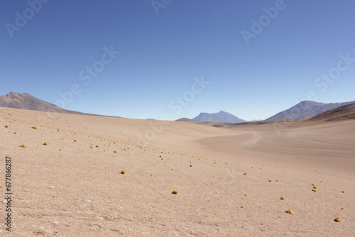 Bolivian Desert Under Clear Blue Sky. Vast desert landscape in Bolivia, surrounded by distant mountains under a bright blue sky