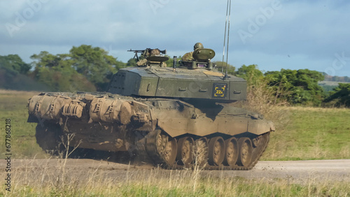 Commander and gunner directing a British army FV4034 Challenger 2 ii main battle tank moving along a dirt track at speed, on a military exercise, Wiltshire UK