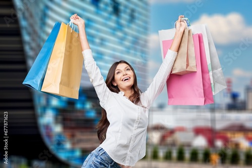 Happy young woman holding a lot of shopping bags