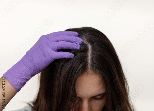 millennial woman with pills in hand brushing hair with wooden comb.hand in surgical glove,doctor,therapist or cosmetician examining girl scalp. female blowing tablets capsules from palm.pills at eyes.