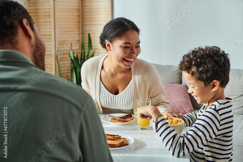 focus on jolly african american woman looking at her son with blurred husband in front of them