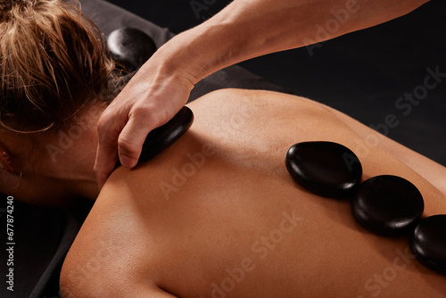 A man receives a hot stone massage, a masseur gives a stone massage