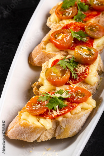 Starter or antipasto - Bruschetta with slices of Spanish sausage on French bread with cherry tomatoes and mozzarella cheese