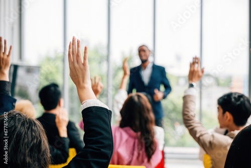 In a conference and convention at a corporate event businesspeople raise their hands to ask questions and vote. The meeting training seminar and discussions emphasize teamwork and collaboration. photo