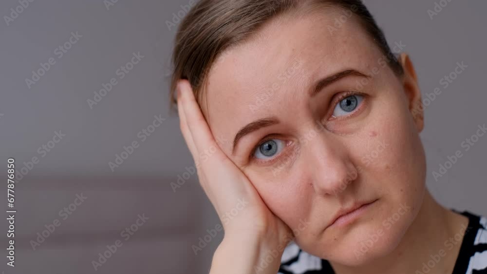 Lonely young woman sitting on bed. Depressed woman at home looking sadly at camera. Close up. Lonely young woman sitting on bed. Depressed woman at home looking sadly at camera. Close up.
