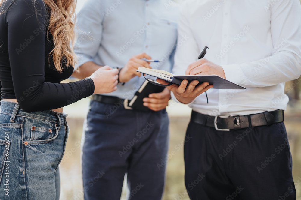 University students studying outdoors, discussing subjects, exchanging knowledge, and preparing for exams. They work as a team, successfully solving problems in a park.