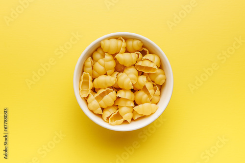 Uncooked gnocchi pasta. Raw italian pasta in bowl on yellow background. photo