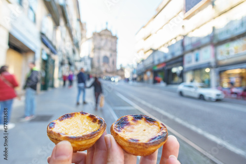 Tow Hand with Portugal's traditional sweet dessert Pastel de nata egg custard tart pastry with street in Porto, Portugal