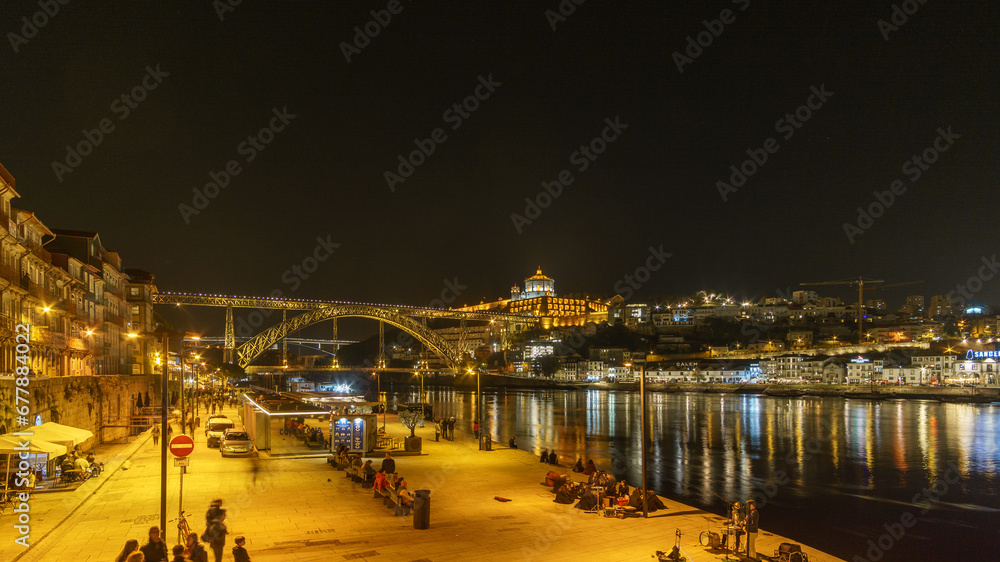 Night view at Ponte Dom Luis seen from Ribeira do Porto with reflection of lights on water surface of Douro River, Porto, Portugal