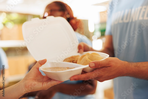 Photos Detailed view of less fortunate woman receiving free food from male volunteer at outdoor food bank
