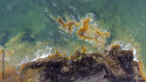 Aerial photo the ocean waves braking on the shores in Canary Islands - Lanzarote: from above with strong waves in blue torquise ocean Cliffs and rocks with ocean by drone. Green Yellow contrast photo