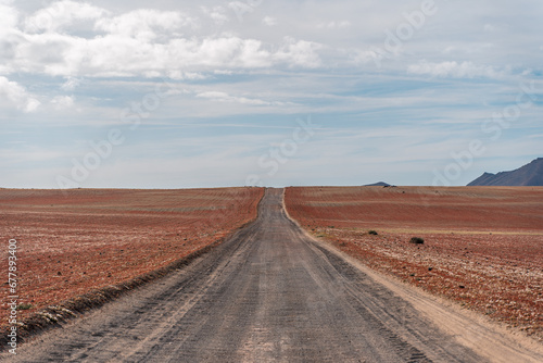 Long emplty lonely dirt road long route ahead volcanic lunar landscape no people, lanzarote, canary islands, spain