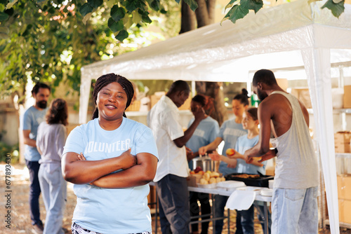 African american female volunteer smiling and posing at a food drive nonprofit event. Charitable initiative program providing hunger relief and support to homeless people and those living in poverty. photo