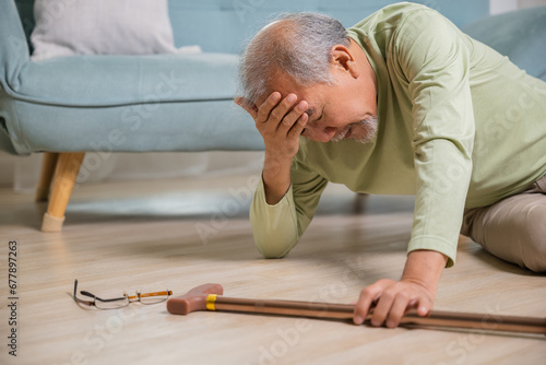 Older senior man headache lying on the floor after falling down he pain and hurt from osteoporosis, Elderly man falling on the floor alone with walking stick at home, Health care and medicine