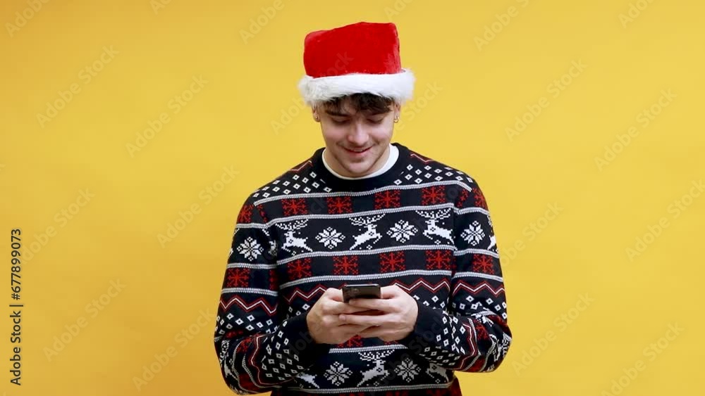 caucasian young man wearing santa claus hat typing with mobile phone with successful expression isolated on background caucasian young man wearing santa claus hat typing with mobile phone with successful expression isolated on background