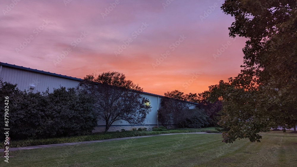 Scenic view of a beautiful sunset visible behind a one-floor building Scenic view of a beautiful sunset visible behind a one-floor building
