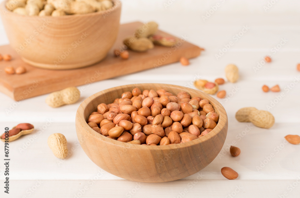 Peeled and unpeeled peanuts on wooden table Peeled and unpeeled peanuts on wooden table