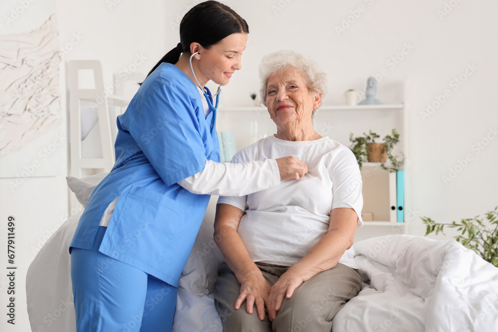 Female nurse hearing senior woman with stethoscope in bedroom Female nurse hearing senior woman with stethoscope in bedroom