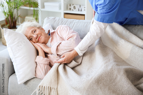 Female nurse caring about lying senior woman at home