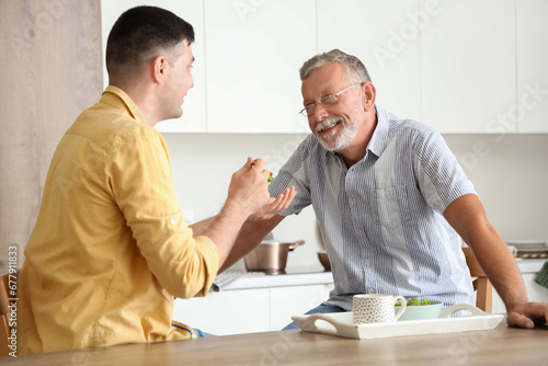 Young man feeding his fathe...
