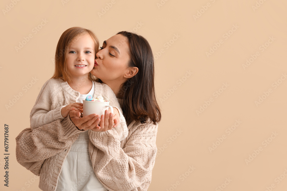 Young mother and her little daughter with mug of hot chocolate on beige background Young mother and her little daughter with mug of hot chocolate on beige background